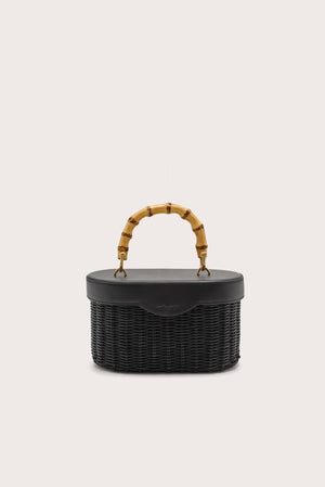 Black woven handbag with bamboo handle on a light beige background