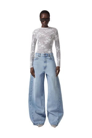 Person wearing a lace top and wide-leg jeans on a white background