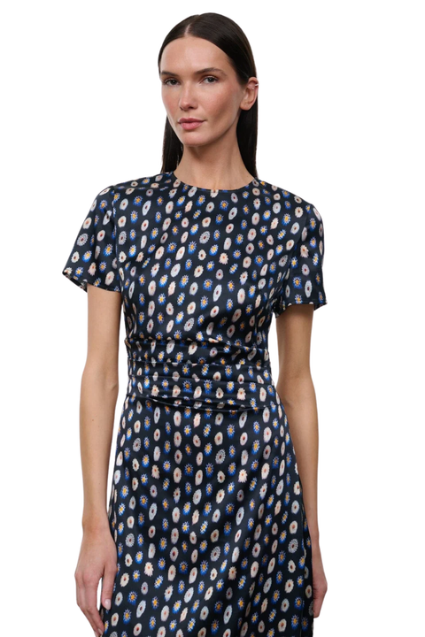 A woman modeling a short-sleeve midi dress with a gathered waist and an all-over abstract circular pattern in navy, cream, and light blue on a white studio background.