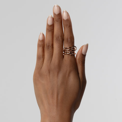 A woman wearing a Spinelli Kilcollin Pisces ring that features two 1.2mm rose gold bands, a 1.7mm rose gold band, and a 2.3mm rose gold band, connected by three rose gold connectors.