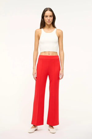 Woman wearing bright red crop flare pants with a front center seam, paired with a white tank and white flats.