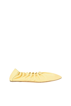 A pale yellow leather slip-on shoe with a gathered, ruched upper and a pointed toe, shown in profile against a solid white background.