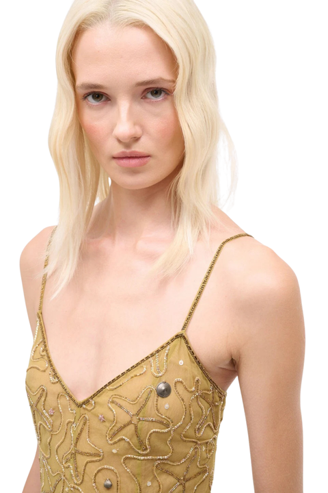 Woman wearing a yellow dress with gold starfish embellishments on a white background close up angle