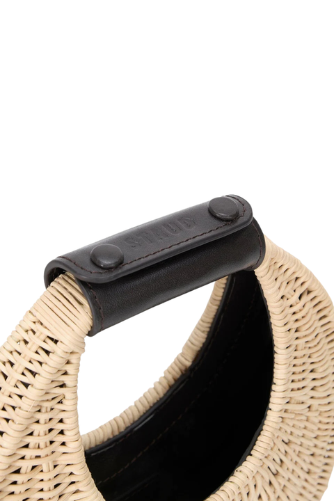Close-up of a woven bag with a brown handle on a white background