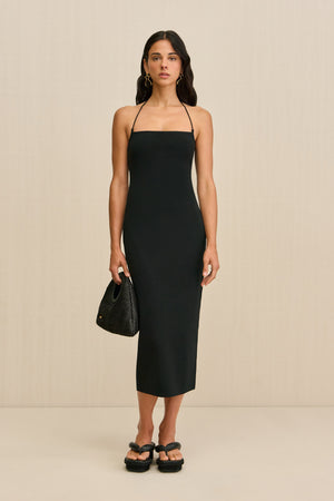 Woman wearing a black midi dress with spaghetti straps and a square neck.