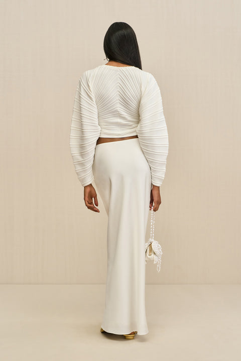 Back-facing woman wearing a white structured cardigan paired with a white maxi skirt.