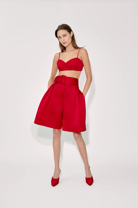 Woman wearing a red outfit with a top and high-waisted shorts on a white background