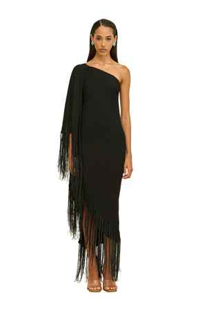 Woman wearing a black one-shoulder dress with fringe details on a beige background