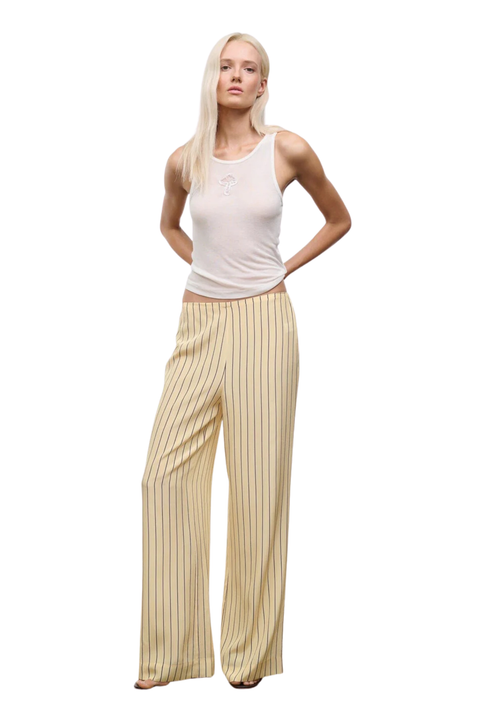 Woman wearing a white tank top and yellow striped silk pants on a white background