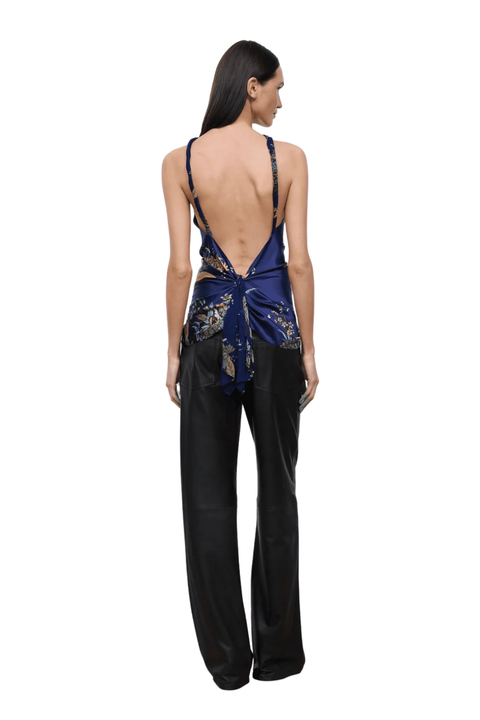 A woman shown from the back wearing a dark blue and black satin wrap top with floral embroidery and black wide-leg pants, set against a plain white background.
