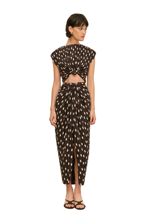 Woman wearing a brown and white polka dot midi dress with a cutout on a white background