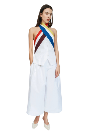 A woman wearing a white top with rainbow halter neck ties
