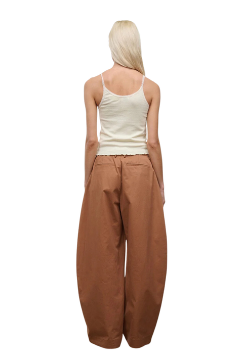 A woman shown from the back wearing a cream ribbed tank top and very wide-leg brown pants, isolated on a white background.