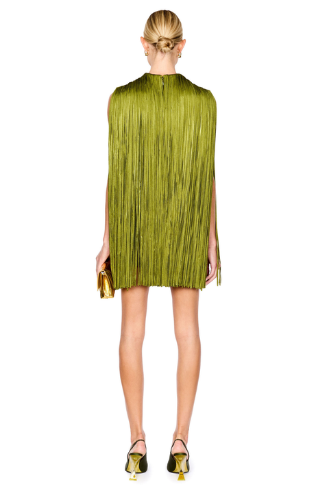 A model shown from the back wearing a sleeveless olive green pleated mini dress with fringe details, paired with green and yellow heels and holding a matching gold clutch, against a plain white background.