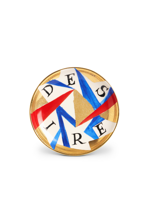 A round earthenware plate with 'DESIRE' text and geometric shapes in red, white, and blue colors, edges highlighted with a gold rim.