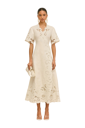 Woman wearing an off white embroidered midi wrap dress on a white background