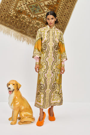 Woman wearing a multicolor, midi length, long sleeve shirt dress that features a point collar, balloon sleeves, and a self tie belt, paired with orange heels.
