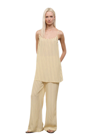 Woman wearing a yellow striped two piece pants and sleeveless top set on a white background