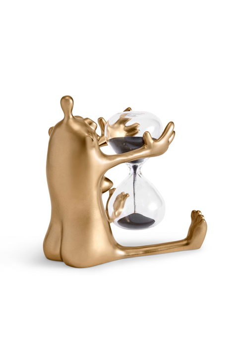 Back of small gold figurine holding glass sand timer.