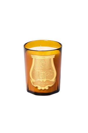 An amber murano glass jar candle with a gold crest emblem on the front, photographed against a solid white background.