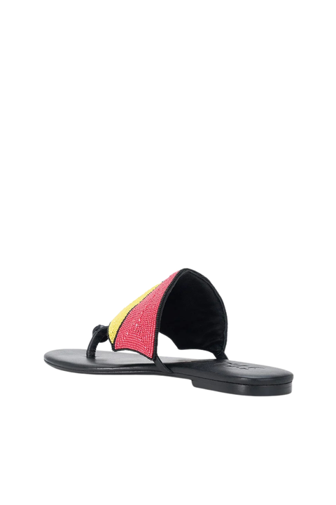 A single black flat sandal with a wide strap featuring a diagonal pattern of pink, yellow, and red panels, shown against a plain white background.