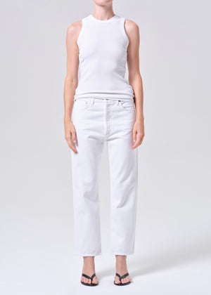 Person wearing a white sleeveless top and high-rise, straight leg, white jeans on a plain background from the front