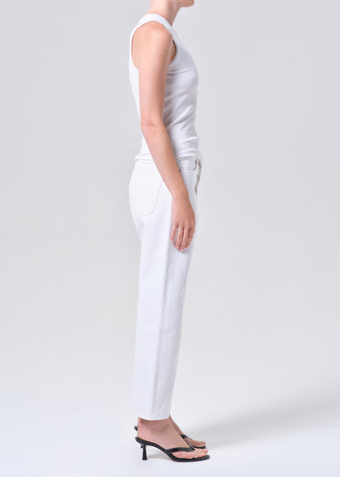 Person wearing a white sleeveless top and high-rise, straight leg, white jeans on a plain background from the side