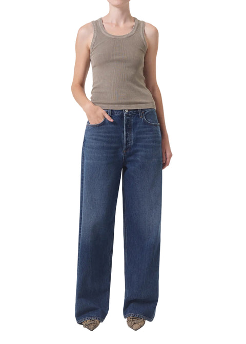 Person wearing a beige tank and dark wash navy blue straight leg midi jeans with hand in pocket