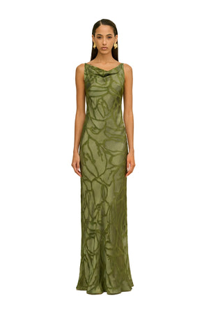 Woman wearing a green evening gown against a beige background.