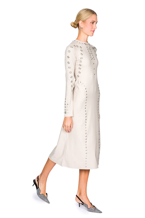 Woman stepping to the side in a long, light-colored dress with snap details on a white background