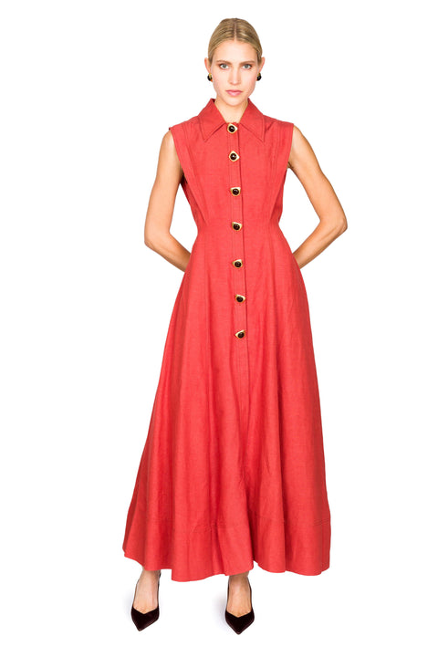 Woman posing with arms behind back wearing a red sleeveless dress with buttons on a white background with hands behind her back