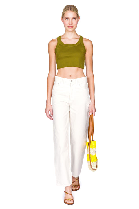 Woman posing in green cropped tank and jeans and brown shoes.