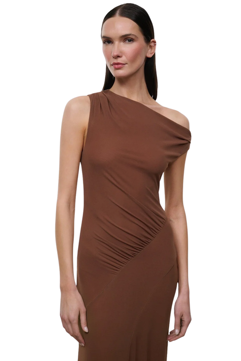 A woman modeling a one-shoulder ruched midi dress in a warm brown color, photographed against a solid white background.