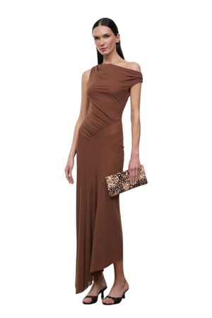 A woman modeling a brown off-the-shoulder maxi dress with ruched detailing at the waist, holding a leopard-print clutch, against a plain white background.
