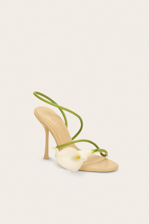 High-heeled shoe with lily and green strap on a white background taken at an angle.