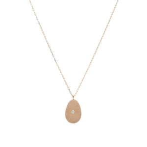 A tan, oblong stone pendant that is embellished by a round diamond in the center and accented by two small diamonds above and below, suspended on a yellow gold paperclip chain.