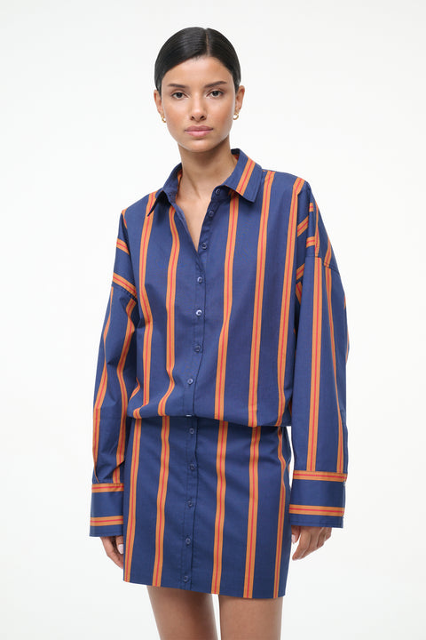 Close up of a woman wearing a blue and orange striped long sleeve mini dress.