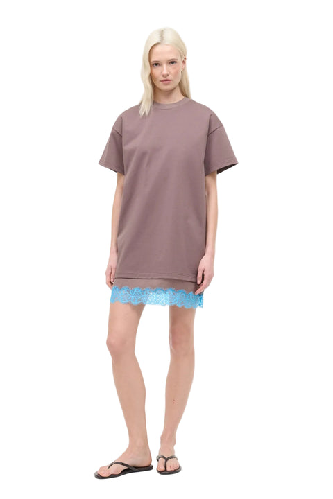 Woman wearing a brown oversized t-shirt dress with blue lace trim on a white background