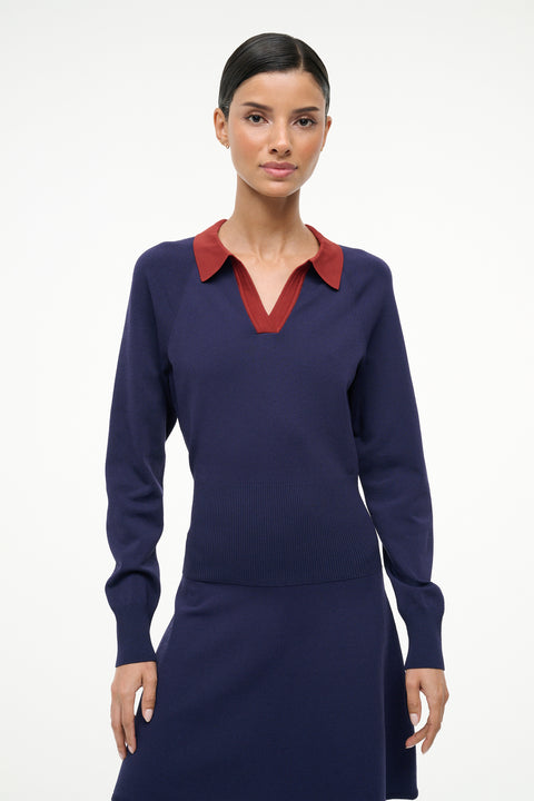 Woman wearing a navy dress with a red collar against a white background