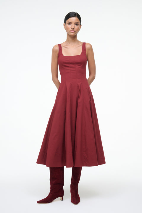 Woman wearing a red dress and matching knee-high boots on a white background