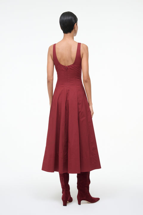 Woman wearing a burgundy dress with open back on a white background