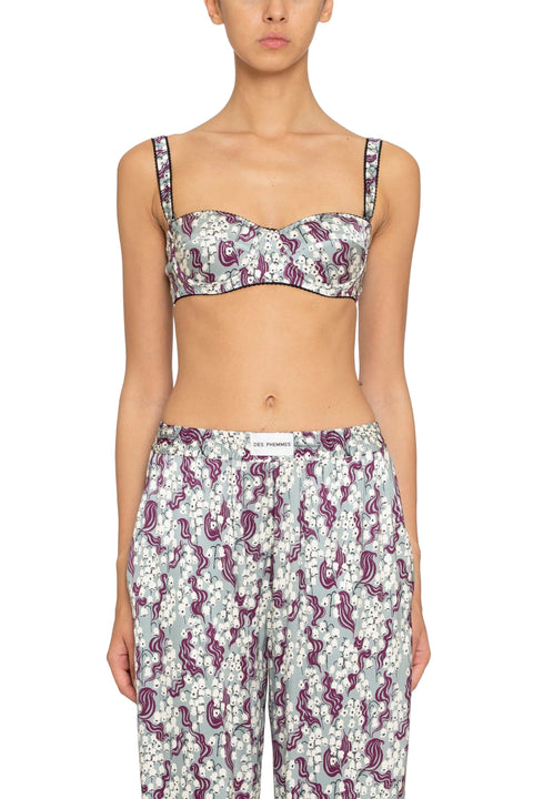 Woman wearing a floral patterned underwire bra top and pants on a plain background.