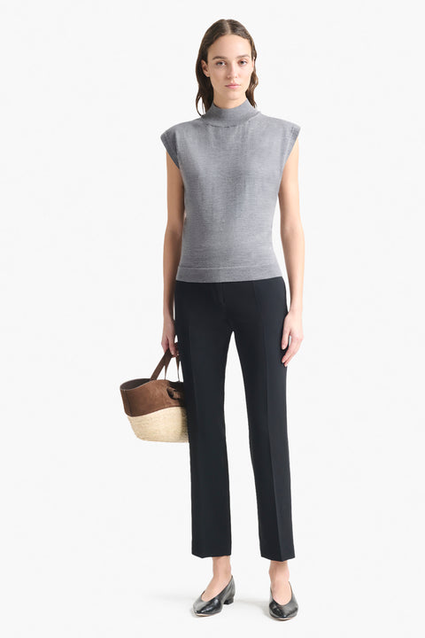 Woman wears grey cap sleeve turtleneck sweater top with black pants.