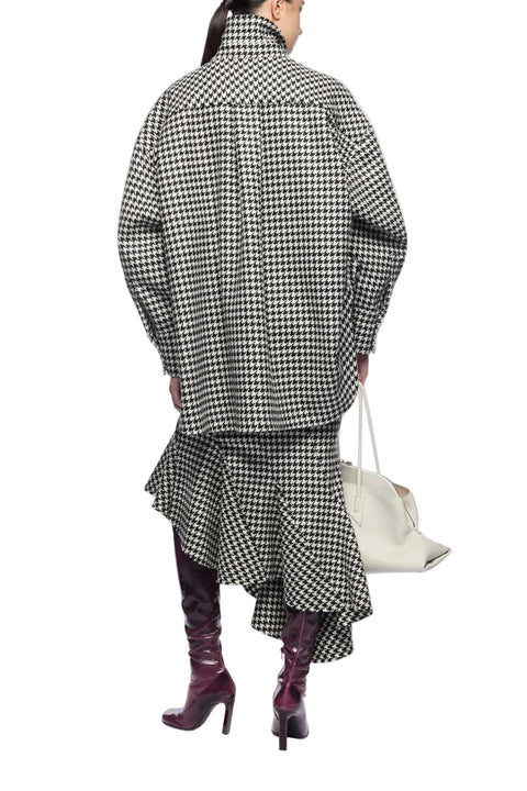 Person wearing a black and white checkered outfit with a white bag on a white background