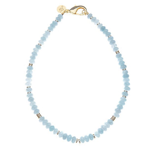 Necklace with light blue bead and small gold beads and gold clasp on a white background