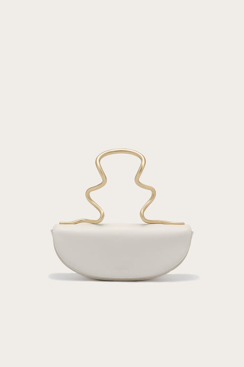 White handbag that features a gold-toned, wavy, sculptural top handle.