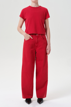 Person wearing a red t-shirt and red wide leg jeans on a white background