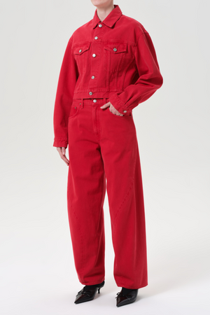 Person wearing red denim jacket and matching jeans on a white background
