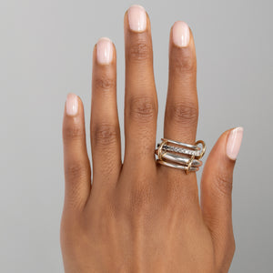 A woman wearing a Spinelli Kilcollin Janssen ring that features a e.11mm sterling silver band, a 2.8mmk sterling silver band pave with ombre white, grey, and black, diamonds, a 3.8mm sterling silver band, and a 2.3mm sterling silver band, all connected by three yellow gold connectors.
