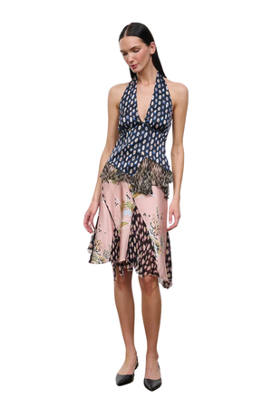 A woman modeling a sleeveless halter-neck top with a navy blue and white pattern on the upper bodice and a pink, black, and beige floral print on the skirt, set against a plain white background.